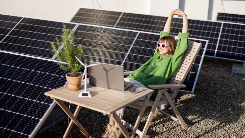 A business professional working on a laptop outdoors next to solar panels, representing sustainable business technology and renewable energy.